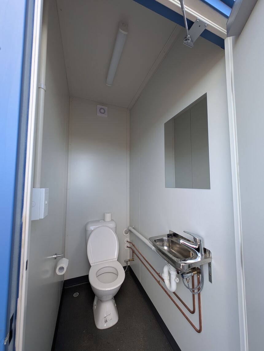 Toilet cubicle in the ablution block with hand basin and mirror