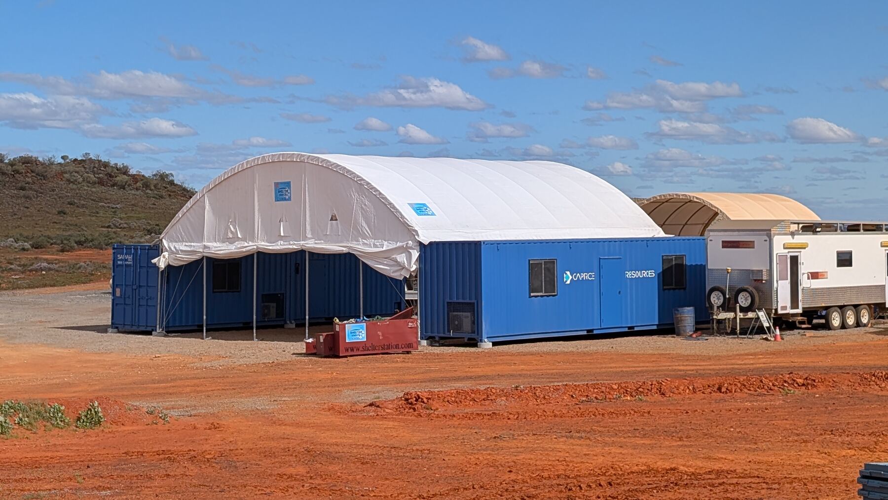 The completed Cue installation: dome shelter workshop spanning the container line on a prepared pad
