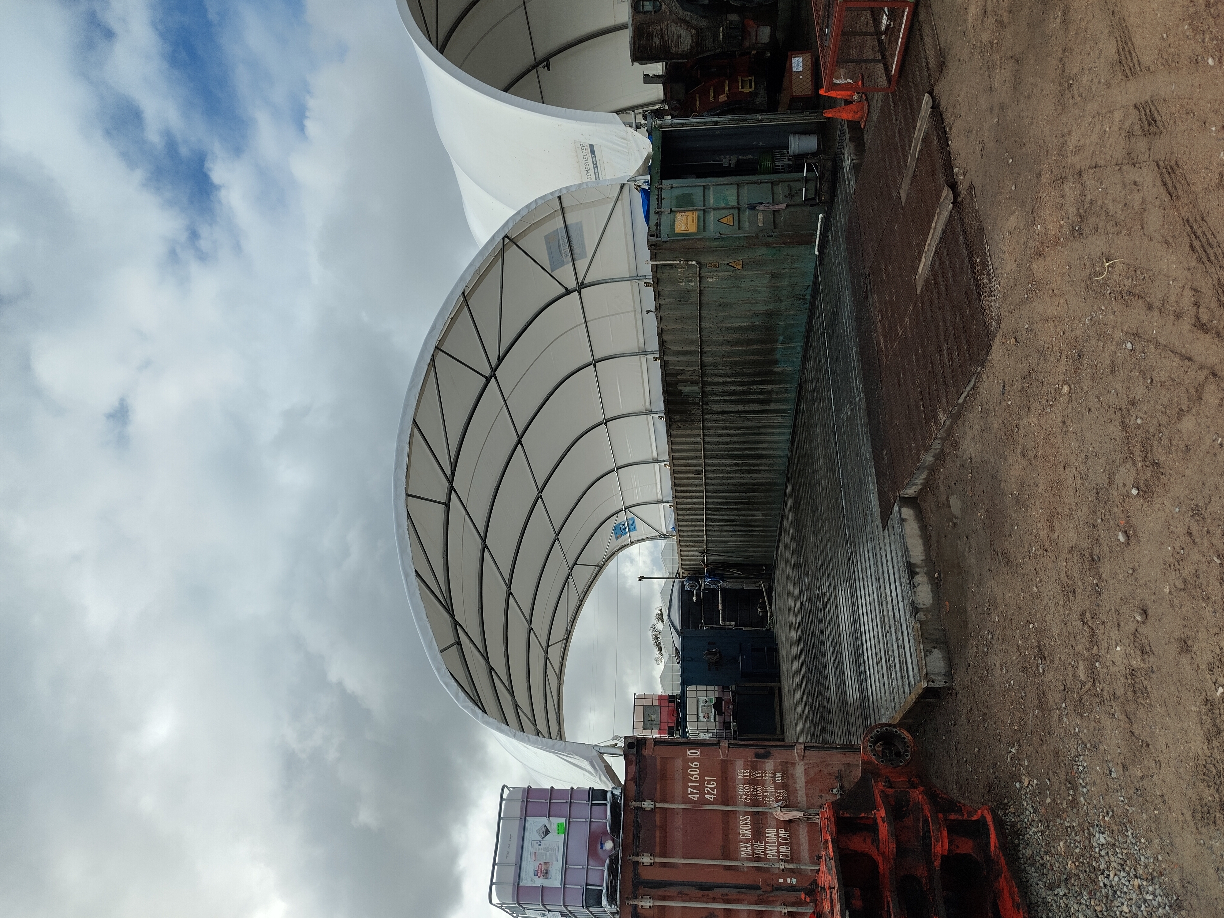 Underside of a dome tarp showing the steel truss frame and tensioning cables
